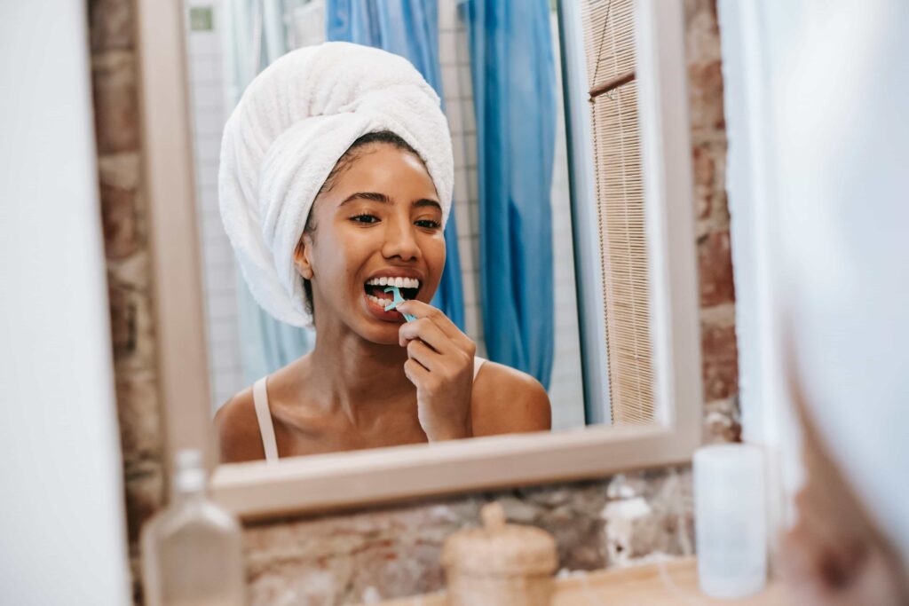 woman flossing her teeth with a floss pick